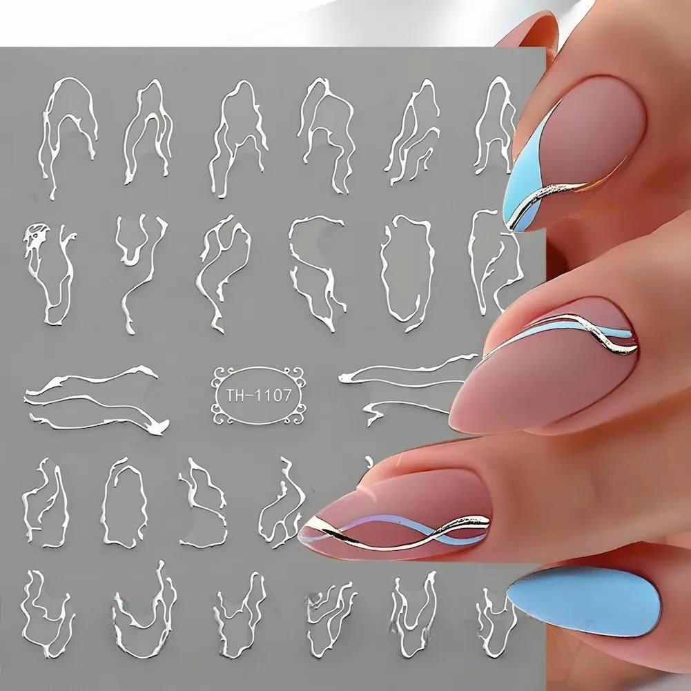 A imagem mostra adesivos para unhas com designs abstratos e ondulados, em tons de prata sobre uma base cinza. As unhas ao lado exibem esses adesivos aplicados em esmalte fosco nude e azul, criando um visual sofisticado e moderno. O código do adesivo é "TH-1107".